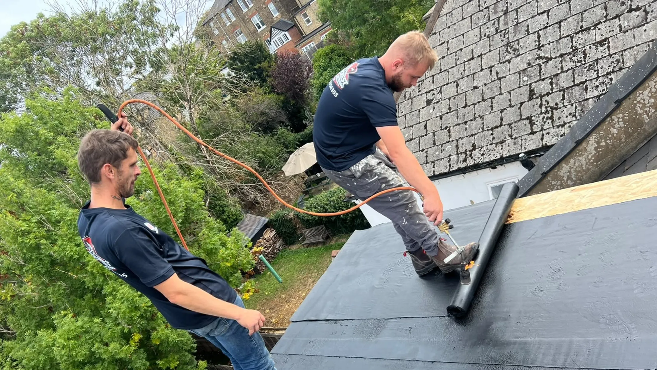 Redcrest roofers in uniform working on a flat roof