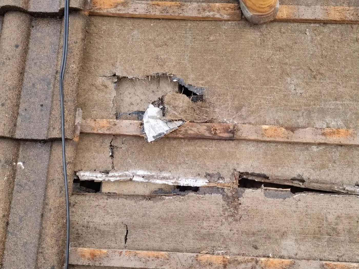 A roofer repairing damaged tiles and flashing